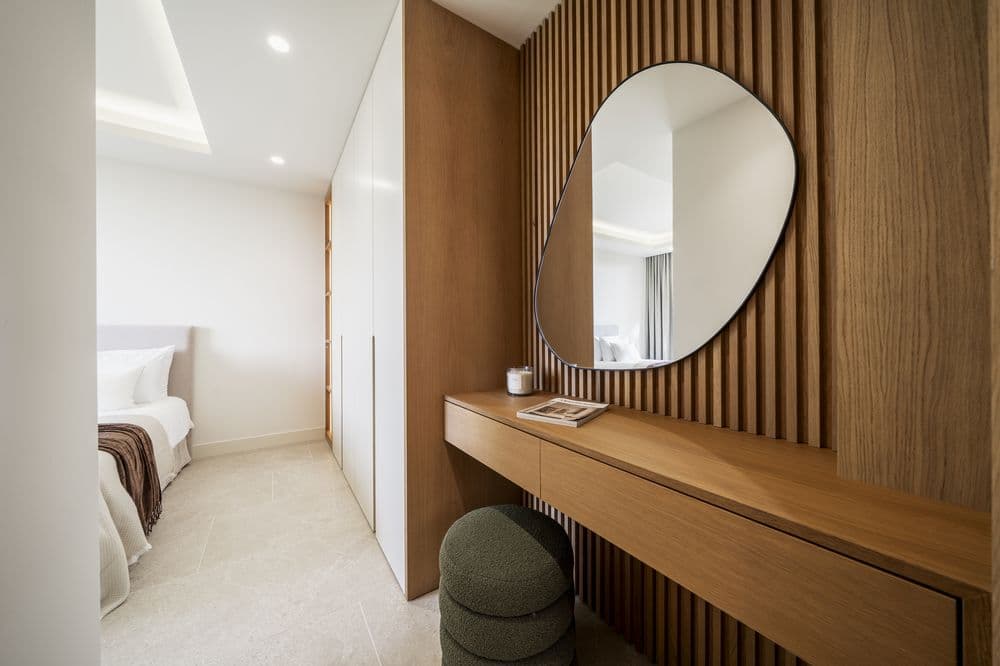 Twin bedroom with round mirror, wood paneling and vanity console