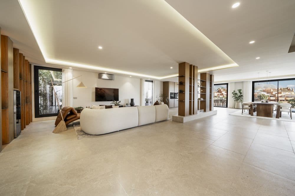 Wide open-plan living room with sofa, TV and floor-to-ceiling windows to the garden