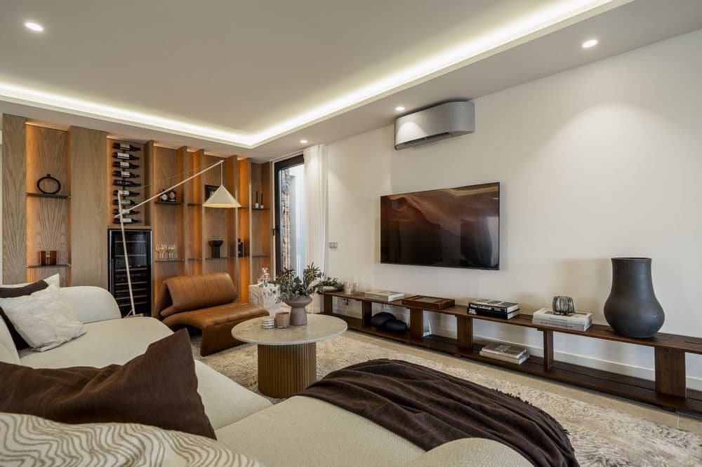 Living room with sofa, leather armchair, TV console and wood shelving