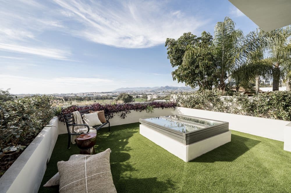 Rooftop terrace with artificial turf, square jacuzzi tub and lounge seating under open sky