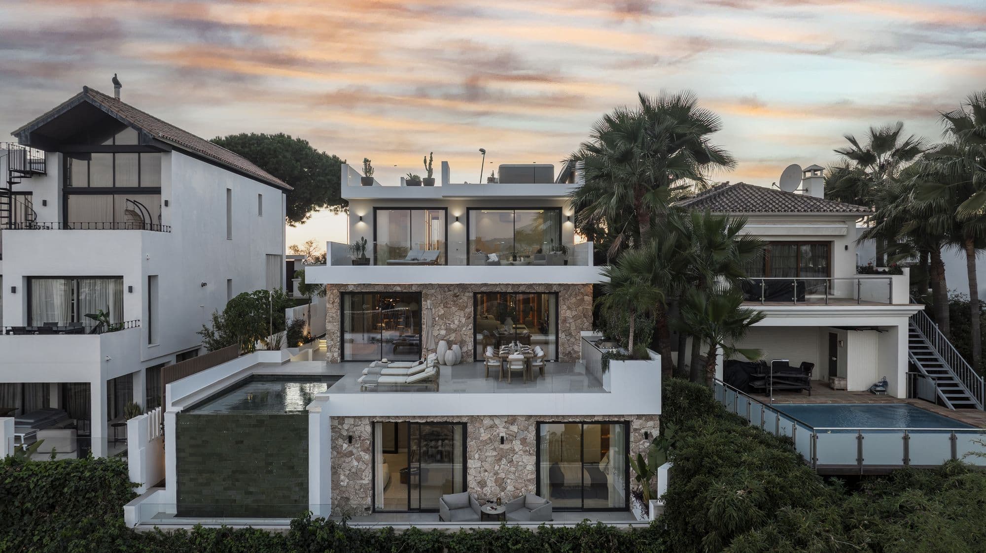 Twilight exterior of the full Villa Tulua facade, stone and white volumes lit at dusk